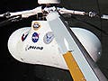 Side-view of a test helicopter in a wind tunnel with a focus on one of the blades.