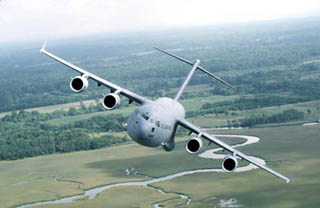 Photo of C-17 transport aircraft banking over a field.