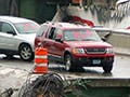 Scene of cars resting on a collapsed bridge.