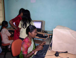 Young girls in India sitting at desktop computers.
