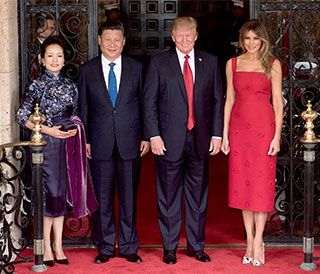 Two smiling, suit-wearing gentlemen are flanked by two elegantly-dressed attractive women. 
