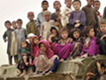 Afgani children gathering on the remains of a tank.