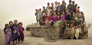 Afgani children gathering on the remains of a tank.