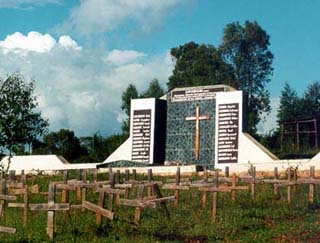 Image of a cemetery and memorial for the Rwandan genocide.  A myriad simple crosses stand in front of a memorial.