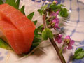 Image depicts a plate with sashimi and a flower.