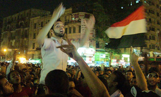 A bearded young man gestures wildly in the middle of a massive crowd.