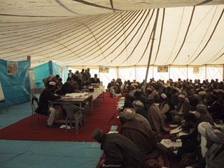 Photo of election officials and voters in a large tent.