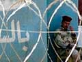 A photo of an Iraqi Army soldier seated behind a barbed wire fence.