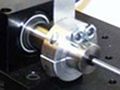 Springs and masses are connected via a shaft sitting on a metal surface.