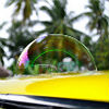 Photo of a large soap bubble on a yellow car with palm trees in the background.
