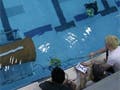 Students attempt to maneuver their robot into a garbage can anchored on its side on the bottom of the pool.