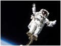 Astronaut Steve Robinson in space, standing on a long robotic arm.