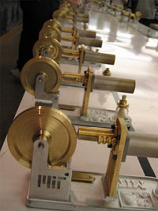 Photo of many, many Stirling engines lined up on a table.