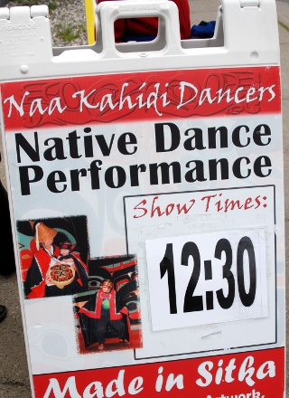 Sidewalk sandwich board advertises the next dance performance at 12:30 by the Naa Kahidi Dancers, located in Sitka, Alaska.