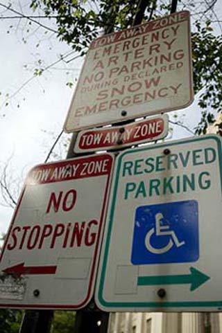 Photograph of four street signs: Reserved Parking, No Stopping, Tow Away Zone, and No Parking.