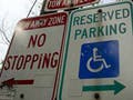 Photograph of four street signs: Reserved Parking, No Stopping, Tow Away Zone, and No Parking.