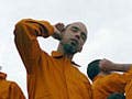 Photo of a small group of adults and children, wearing colored jumpsuits and in various poses of concentrated listening.