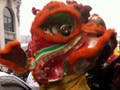 A photograph of a red, orange, and yellow Asian dragon costume on a snowy city street