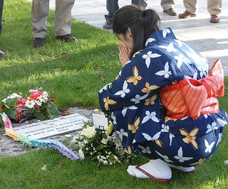 A photo of a woman in a kimono at a memorial for the bombing or Hiroshima and Nagasaki.