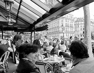 Diners overlook a bustling street at an open air café in Paris.