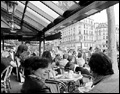 Diners overlook a bustling street at an open air café in Paris.