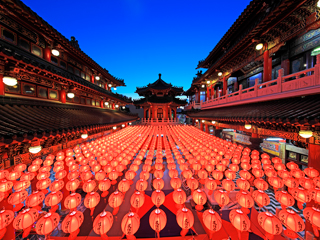 A picture at a Chinese temple with a lot of red lanterns with a blue sky background.