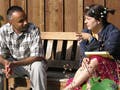 Man and woman sitting on a bench, talking. Woman is gesturing.