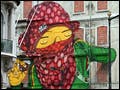 A large image of a woman in a green jacket and a red headscarf has been painted on the side of multi-story building.