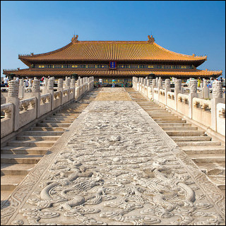 The steps leading up to the Hall of Supreme Harmony in the Forbidden City in Beijing, China. The stairs are separated in the center by a path of dragon carvings. The sky is very blue.