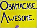 In front of the Supreme Court building, the arm of an unseen demonstrator holds up a huge yellow sign with the words "Obamacare. Awesome."