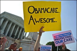 In front of the Supreme Court building, the arm of an unseen demonstrator holds up a huge yellow sign with the words "Obamacare. Awesome."