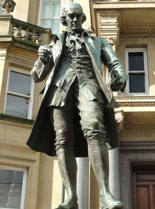 A statue of a formally-dressed man, wearing an overcoat and knee-high boots, holding a scroll in one hand, and compasses in the other.