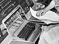 A black and white photograph circa 1960 with four people gathered around the UNIVAC I keyboard, which was the first commercial electronic computer.