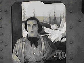 Film still of Buster Keaton sitting in a steam locomotive, facing the viewer.