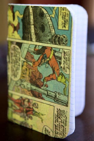 Photo of a grid-paper notebook with comic strip on the cover. The notebook is reinforced with thin cardstock.