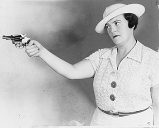A black and white photo of a woman holding a pistol.