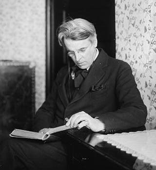 A black and white photo of William Butler Yeats reading a book.