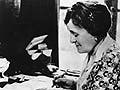 Photograph of Edith Wharton, writing while seated at a desk.