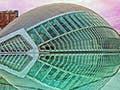 A modern structure made of glass and steel. It curves upwards into a half circle  and is reflected in the pool around it.