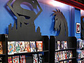 Black display shelves with a variety of comic books, each shelf adorned with a comic book symbol on top.