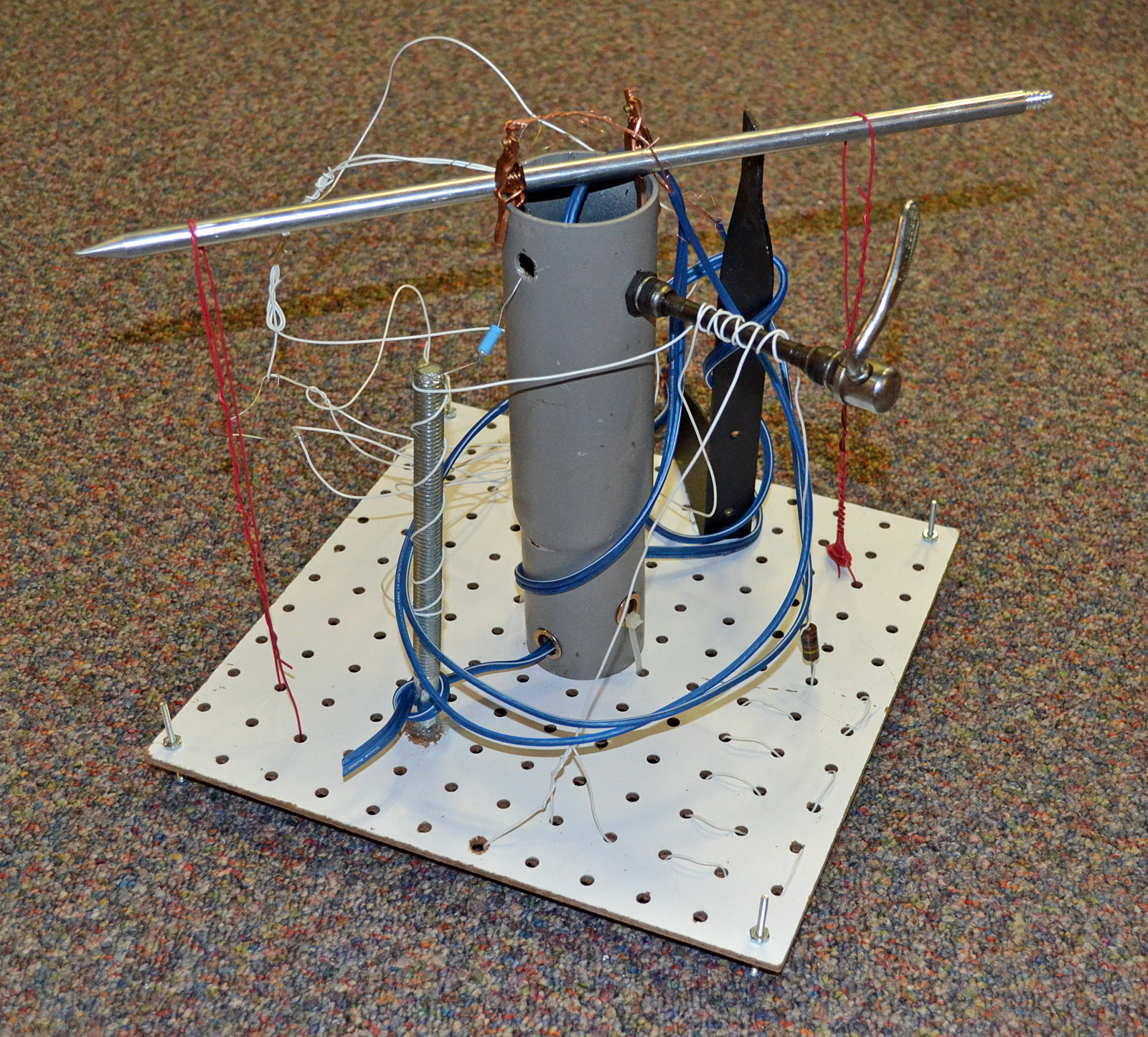 Photo of a sculpture with a vertical metal cylinder, wires, knitting needle, etc.