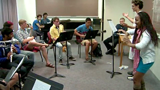 Photo of two students conducting in front of several other student instrumentalists.
