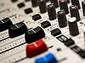 Closeup photo of slides and dials on an audio mixing console.