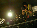 A photographer perched on a catwalk above a stage.