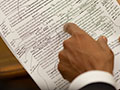A photo of President Obama's hand pointing to a draft of his healthcare speech, which is marked up with edits.
