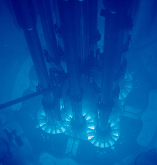 A blue glow suffuses a water-filled chamber containing pipes and other apparatus.