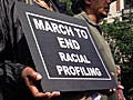 In the midst of other marchers, a black woman holds a sign reading: "March to End Racial Profiling."