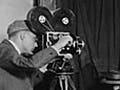 A photo of a cameraman, director and two actors on a set.