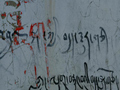Tibetan graffiti on a crumbling plaster wall.
