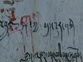 Tibetan graffiti on a crumbling plaster wall.